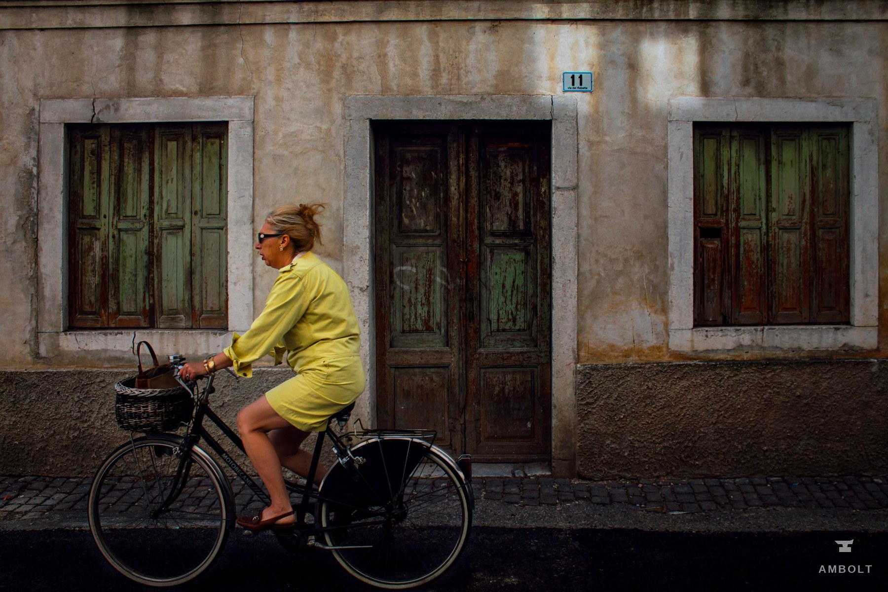 Cyclist in yellow passing a weathered facade